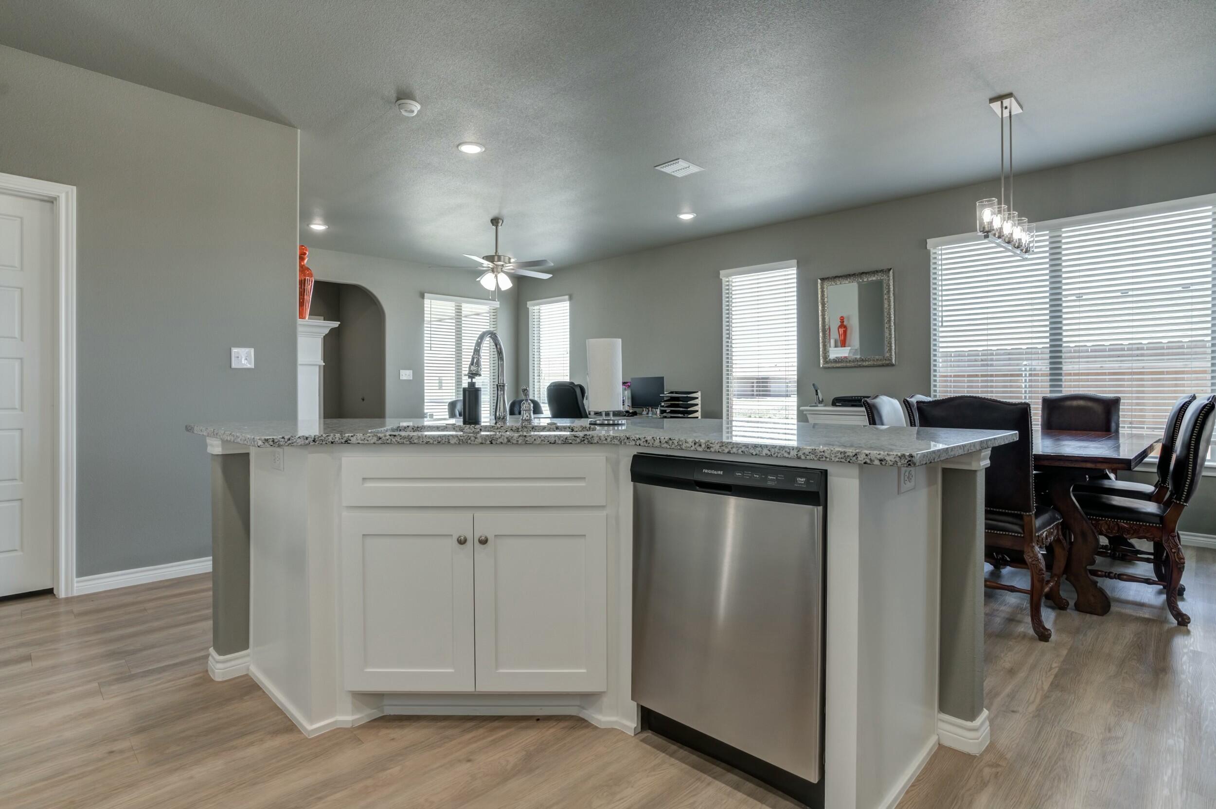6928 11th Street Lubbock, TX 79416 - Photo 21 of 42 a kitchen with kitchen island granite countertop a sink cabinets and wooden floor