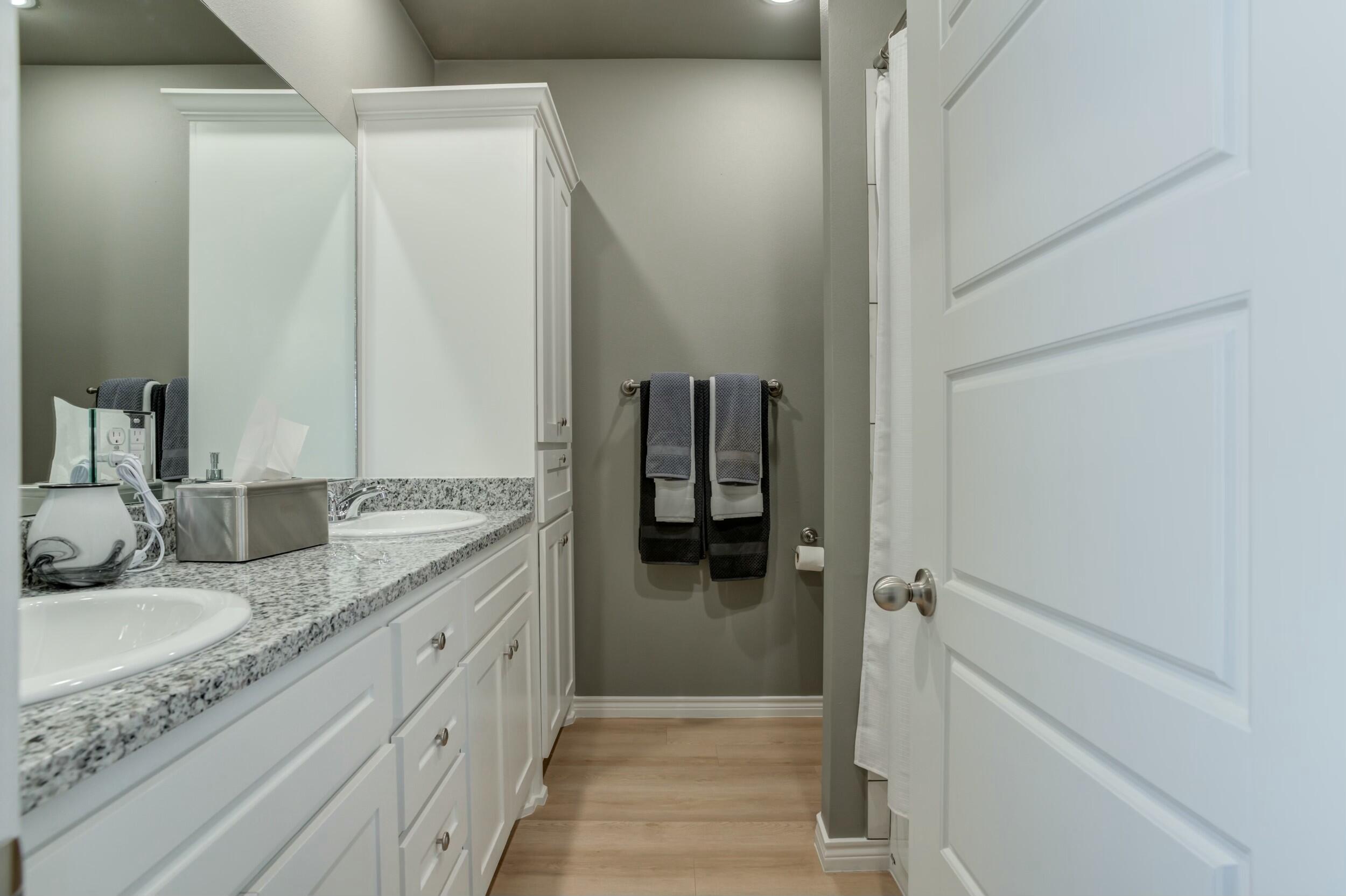 6928 11th Street Lubbock, TX 79416 - Photo 28 of 42 a bathroom with a granite countertop sink and a mirror
