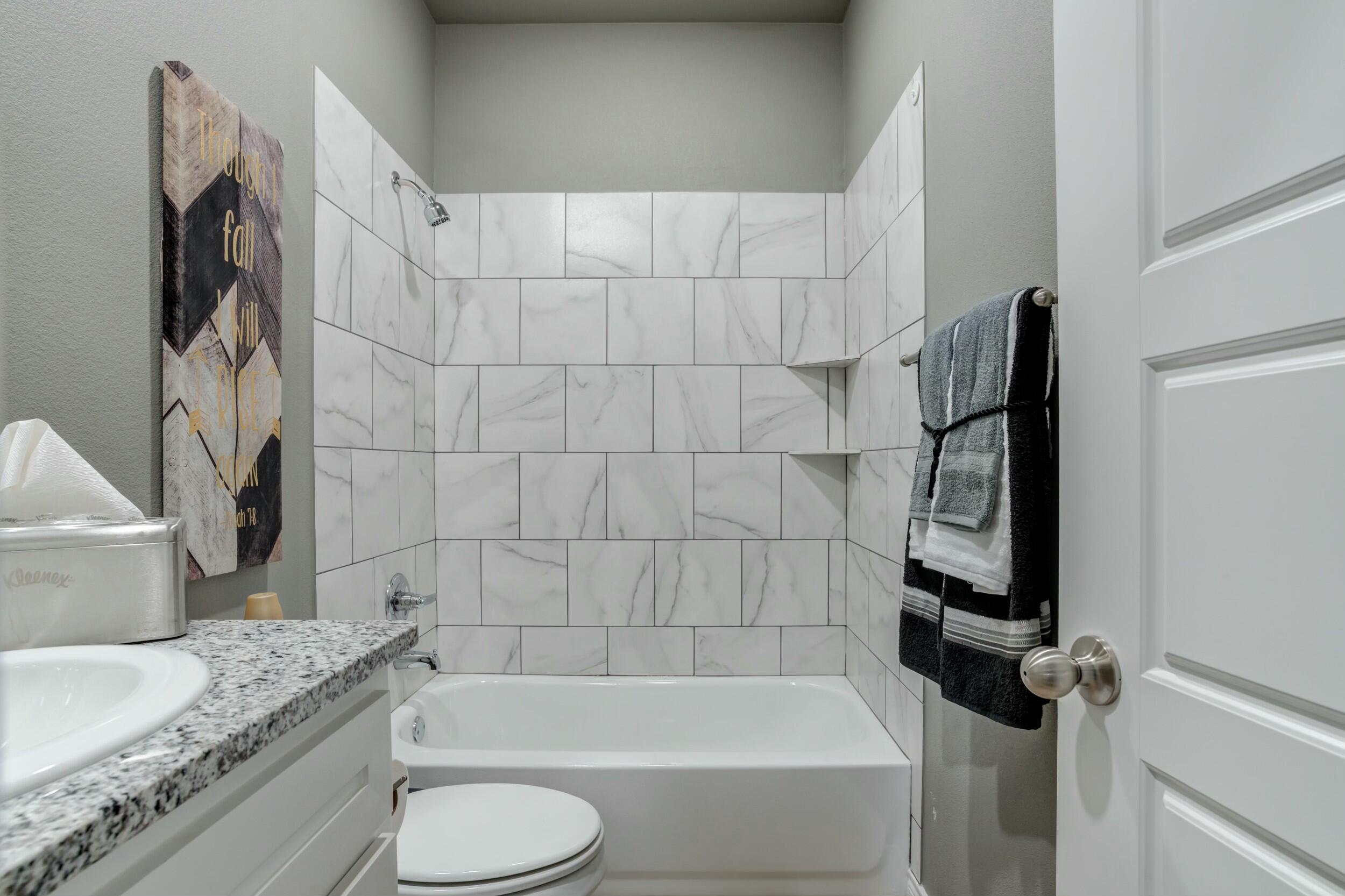 6928 11th Street Lubbock, TX 79416 - Photo 35 of 42 a bathroom with a granite countertop bathtub sink vanity mirror and toilet