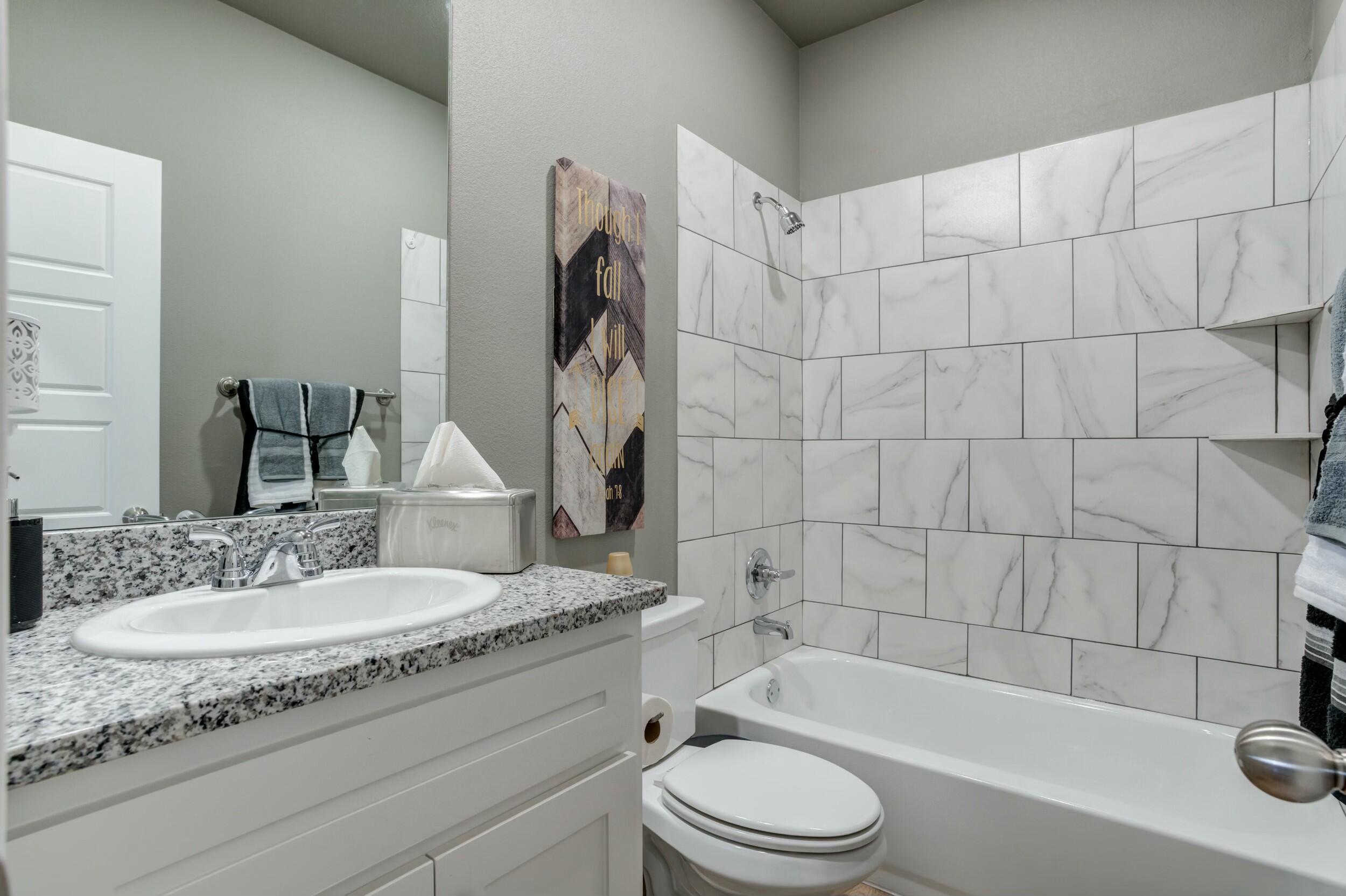 6928 11th Street Lubbock, TX 79416 - Photo 36 of 42 a bathroom with a granite countertop bathtub sink vanity mirror and toilet