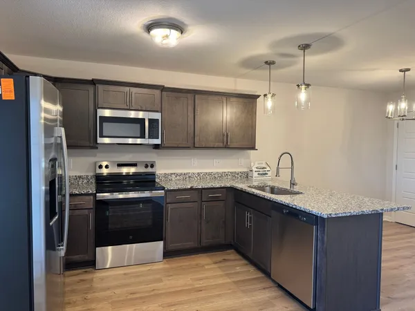 a kitchen with stainless steel appliances granite countertop a sink stove and refrigerator