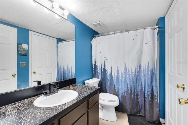 a bathroom with a granite countertop sink toilet and a mirror