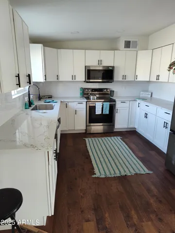 a kitchen with granite countertop a sink cabinets stainless steel appliances and a counter space