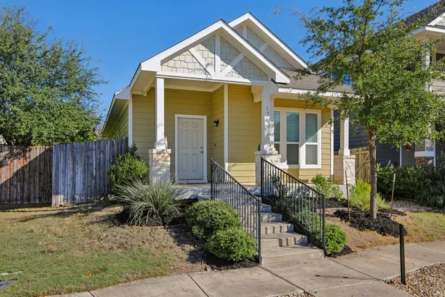 a view of a house with brick walls plants and large tree