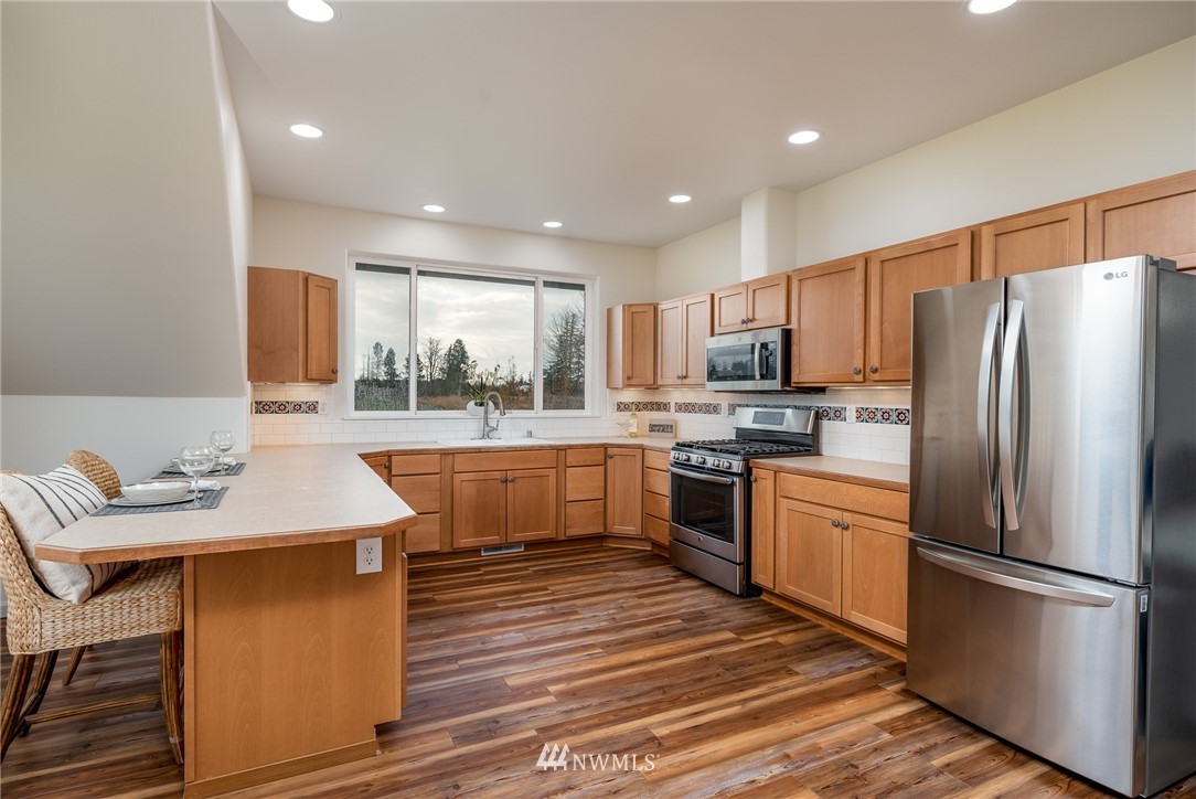 672 East Smith Road Bellingham, WA 98226 - Photo 9 of 25 a kitchen with stainless steel appliances granite countertop a refrigerator a sink dishwasher a stove with wooden cabinets and floor