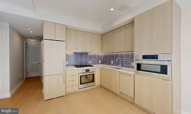 a kitchen with stainless steel appliances granite countertop a refrigerator sink stove and white cabinets