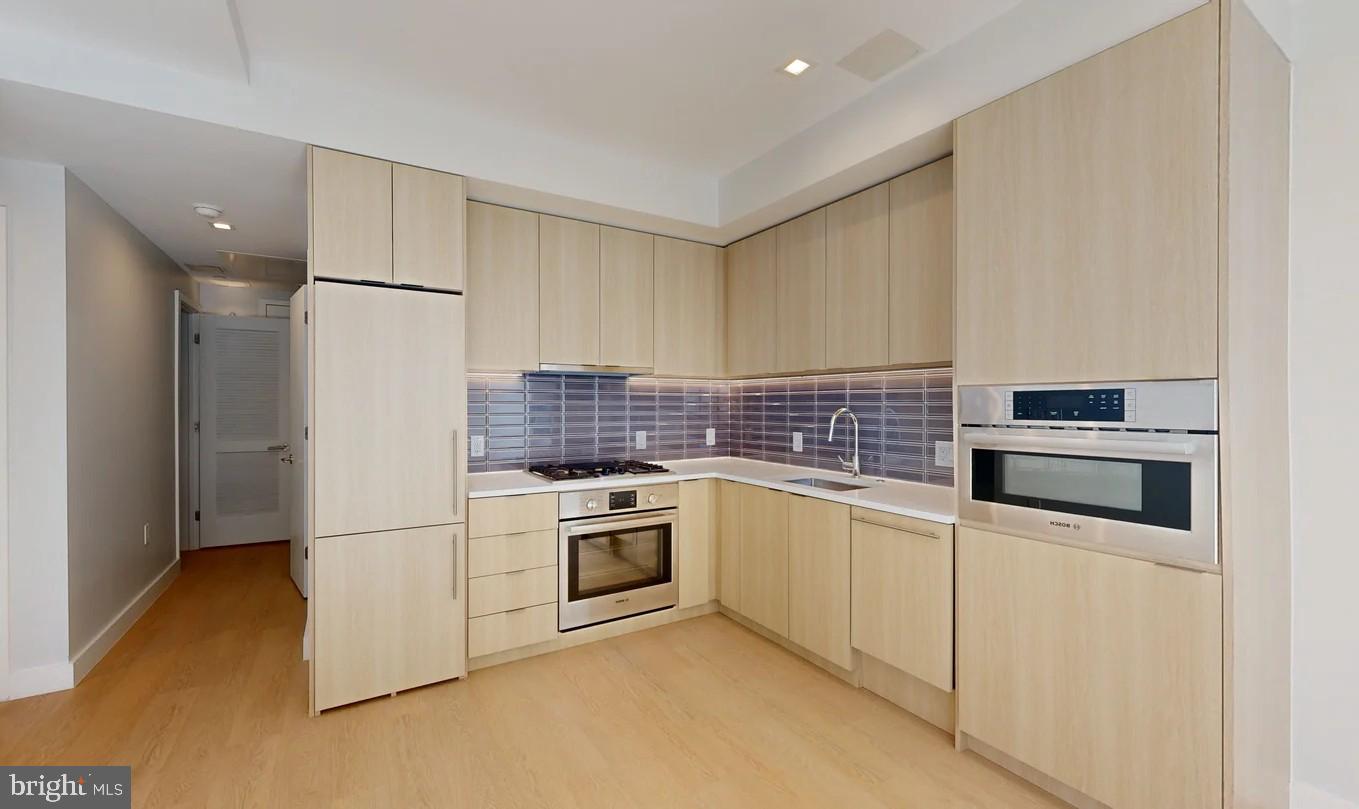 a kitchen with stainless steel appliances granite countertop a refrigerator sink stove and white cabinets