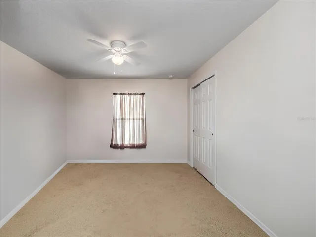 an empty room with chandelier fan and windows