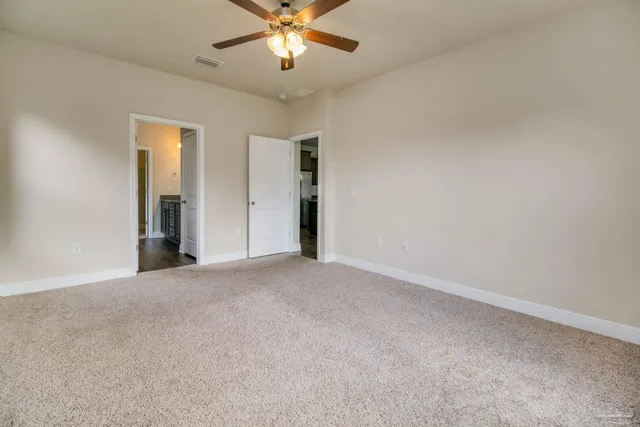 an empty room with a chandelier fan and windows