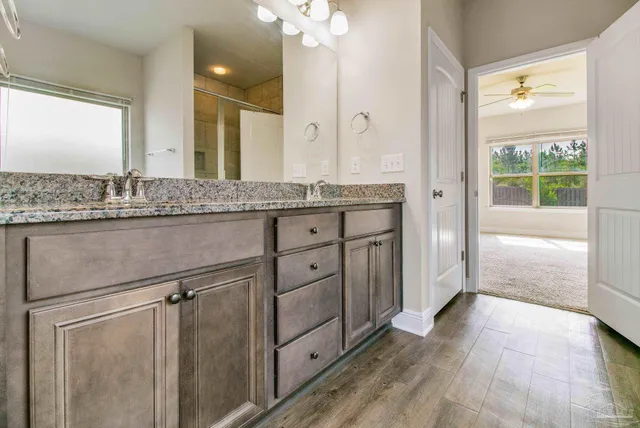 a bathroom with a granite countertop sink a mirror and a shower