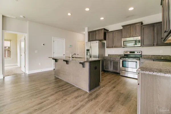 a kitchen with stainless steel appliances granite countertop a refrigerator a stove and a sink