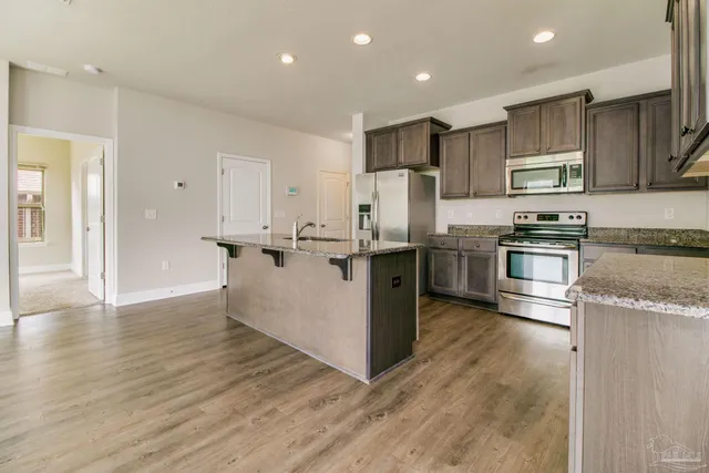 a kitchen with stainless steel appliances granite countertop a refrigerator a stove and a sink