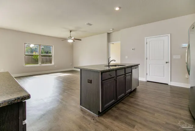 a kitchen with a sink and a stove top oven with wooden floor