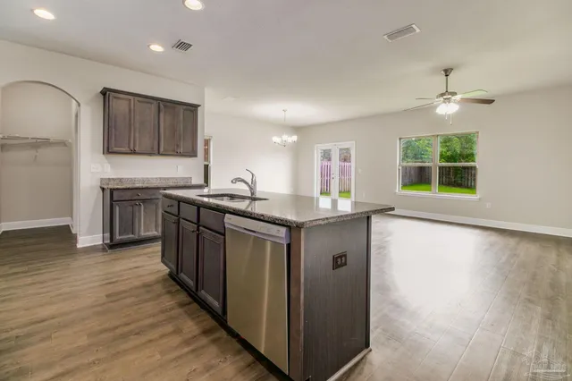a kitchen with stainless steel appliances granite countertop a sink a stove a refrigerator cabinets and wooden floor