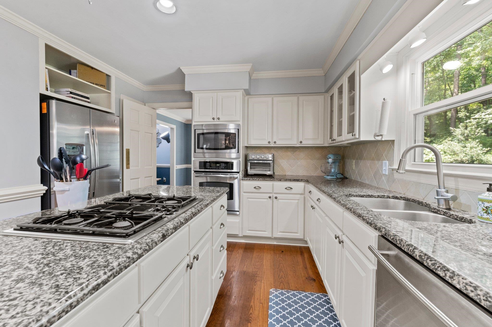 9301 Greenfield Drive Raleigh, NC 27615 - Photo 8 of 48 Kitchen features pantry, island, tile backsplash, and lots of storage including pull out shelves. Kitchen