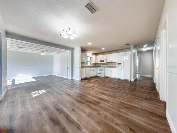 a view of a hallway with wooden floor and a kitchen