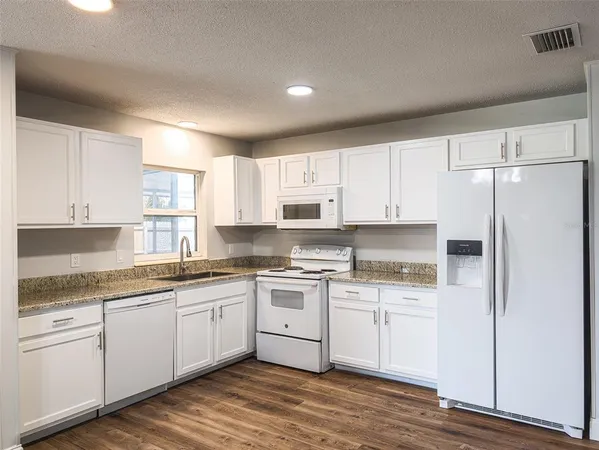 a kitchen with white cabinets sink and refrigerator