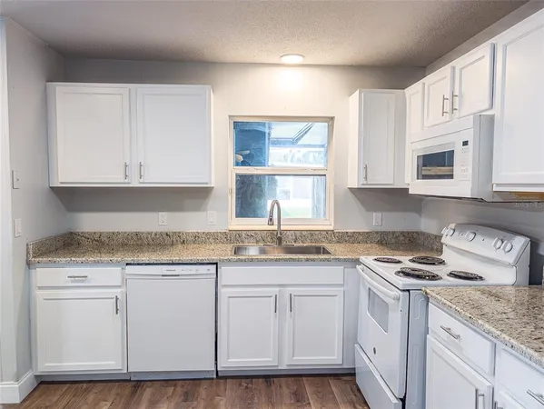 a kitchen with granite countertop white cabinets and white appliances