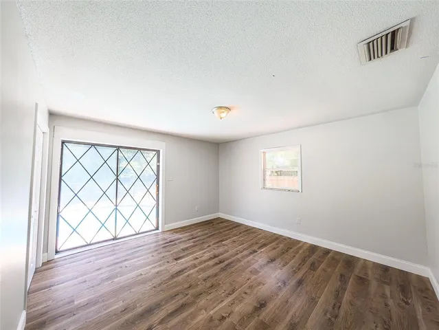 an empty room with wooden floor and windows