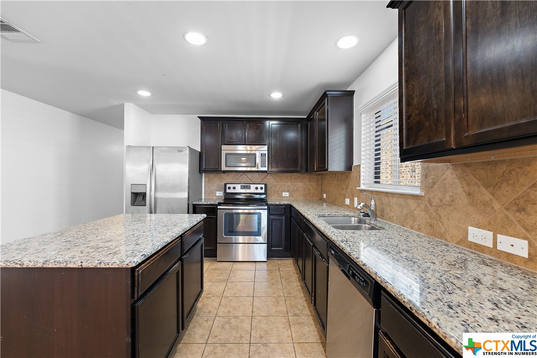 a kitchen with stainless steel appliances granite countertop a sink counter space and refrigerator