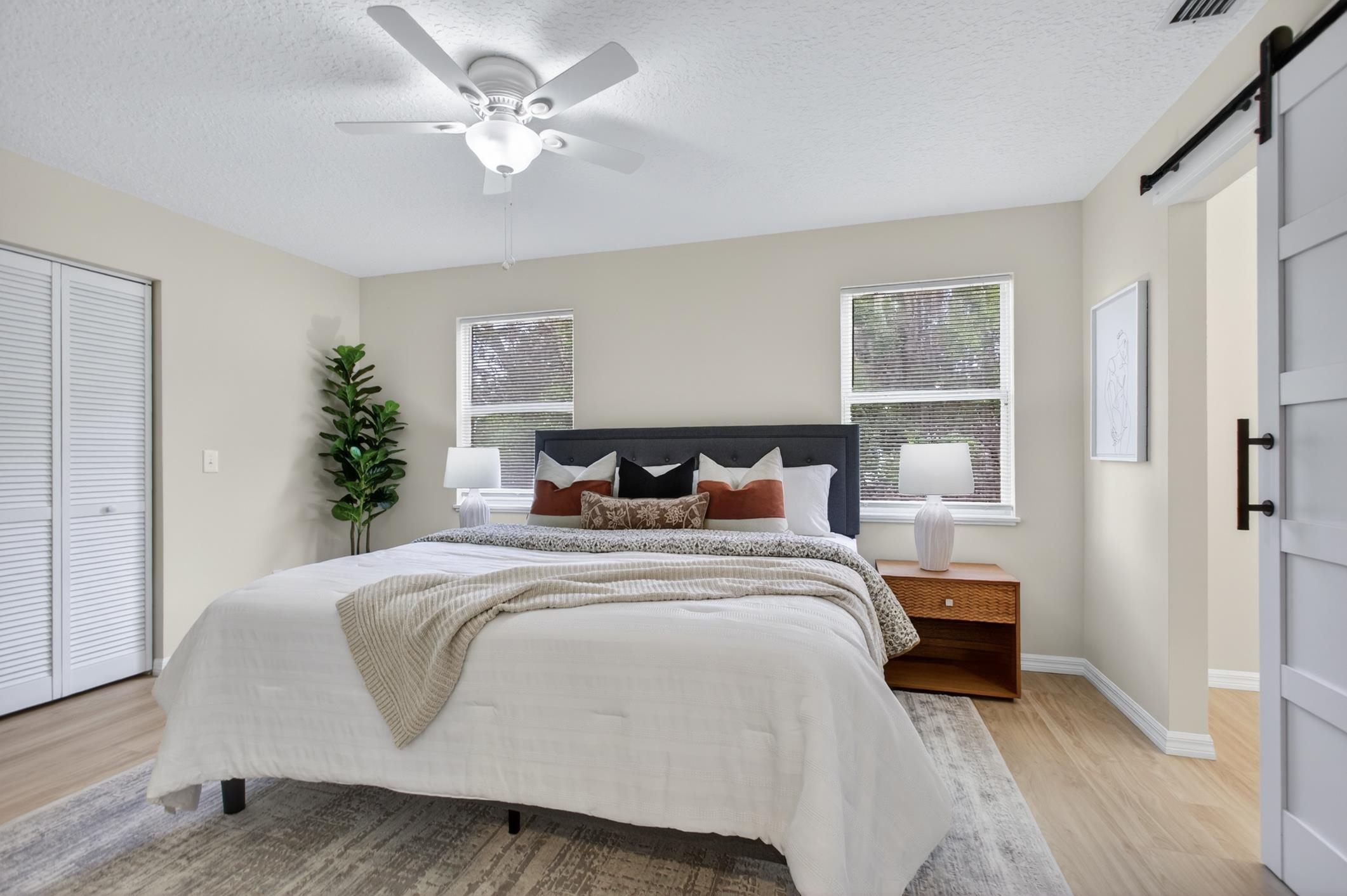 37 Madeore Street St. Augustine, FL 32084 - Photo 25 of 45 Bedroom with a barn door, a textured ceiling, light vinyl plank flooring, a ceiling fan, and a walk-in closet.