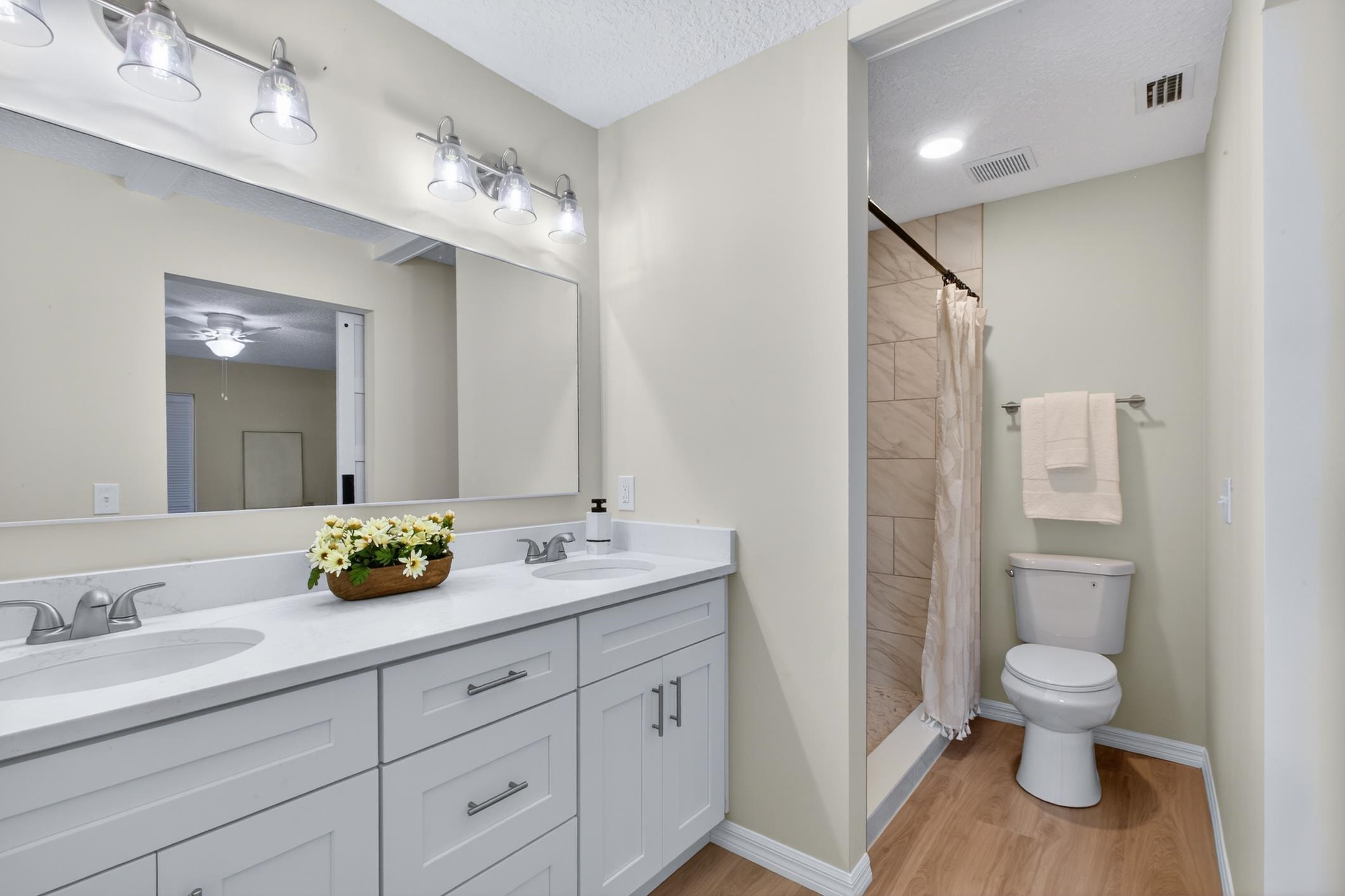37 Madeore Street St. Augustine, FL 32084 - Photo 31 of 45 Primary bathroom features a tiled shower, double vanity, a textured ceiling, and light vinyl plank flooring.