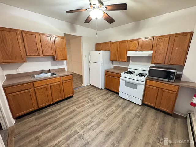 a kitchen with wooden floors and white stainless steel appliances