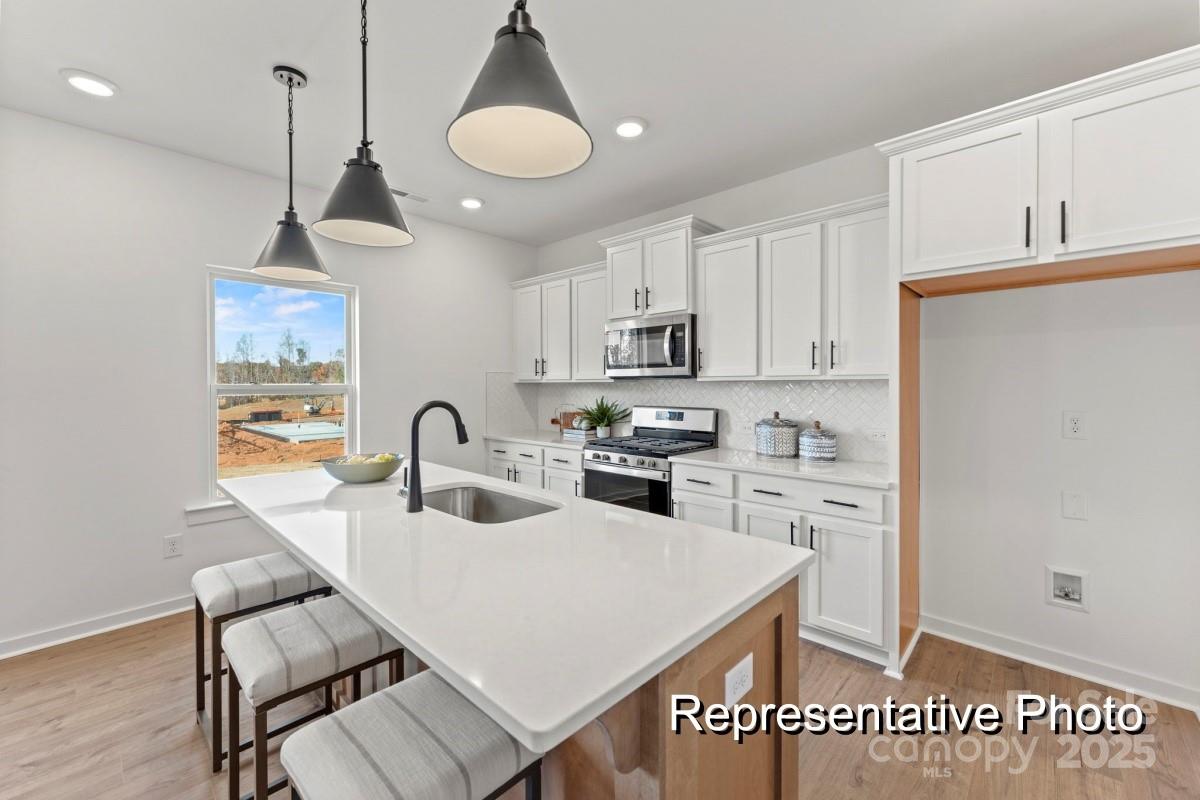 32612 B Millingport Road, Unit 7157 New London, NC 28127 - Photo 3 of 23 a kitchen with stainless steel appliances granite countertop a sink a stove a refrigerator cabinets and chairs