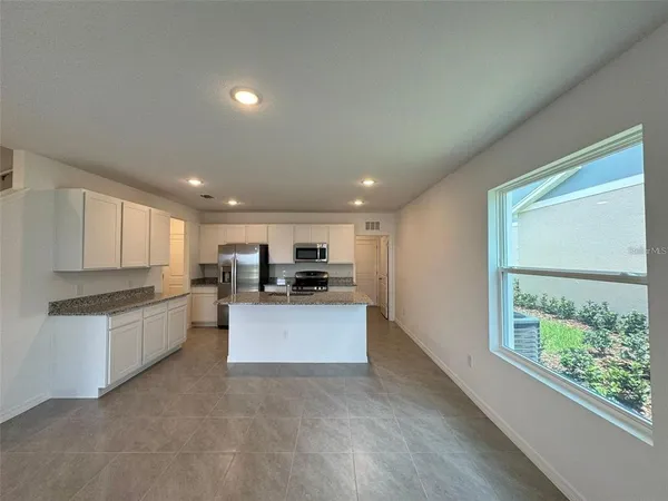 a kitchen with stainless steel appliances kitchen island granite countertop a stove a sink and a refrigerator