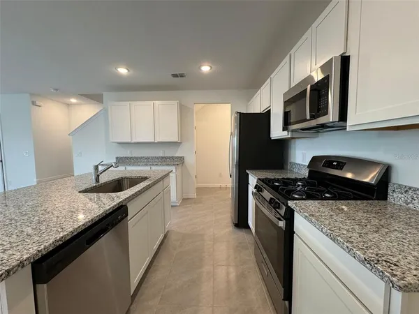 a kitchen with stainless steel appliances granite countertop a sink stove and microwave