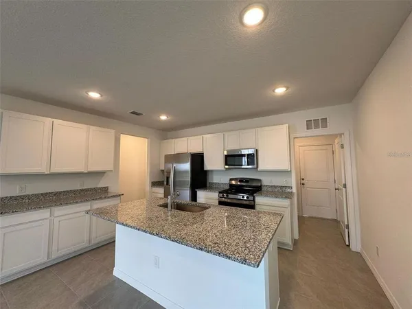 a kitchen with sink a stove cabinets and refrigerator