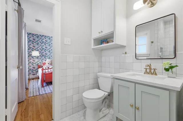 a bathroom with a toilet sink vanity and mirror