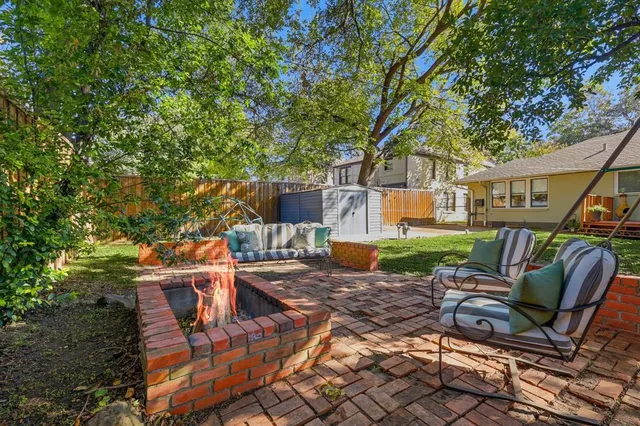 a view of a patio with table and chairs potted plants and large tree