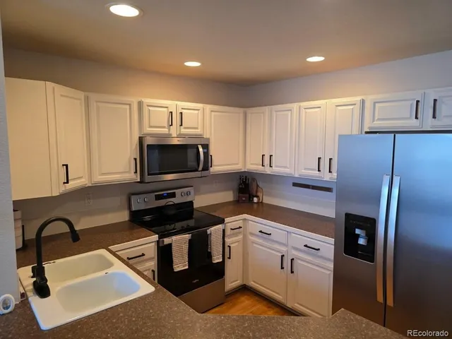 a kitchen with stainless steel appliances a stove a sink a microwave a refrigerator and cabinets