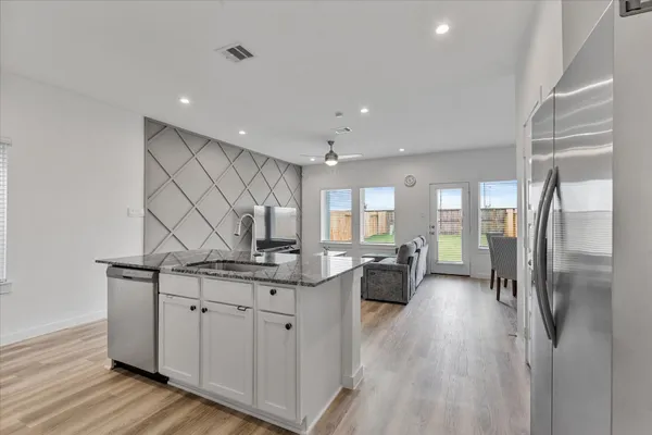 a kitchen with center island wooden floor and stainless steel appliances