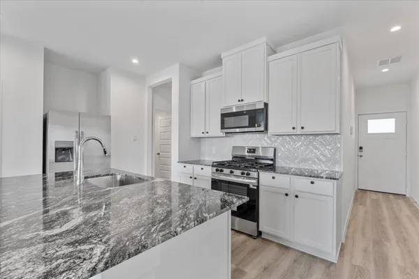 a kitchen with stainless steel appliances granite countertop a stove a sink and a microwave