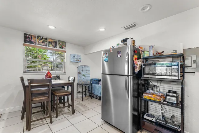 a kitchen with stainless steel appliances a refrigerator a stove a dining table and chairs with the front view