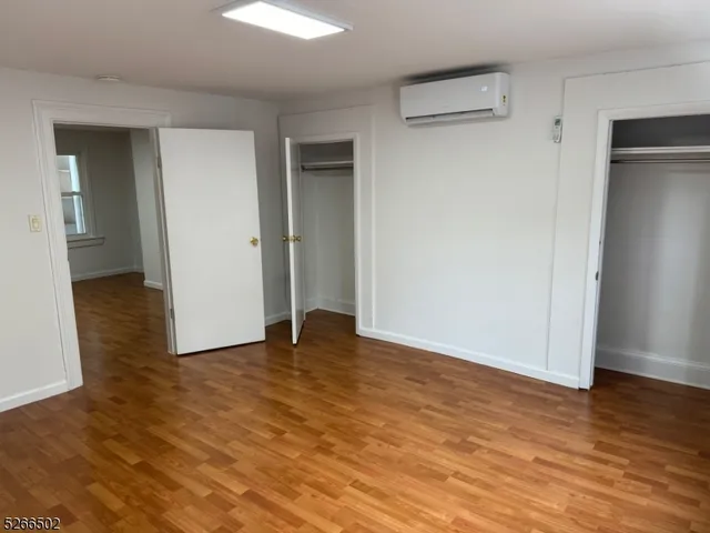 a view of an empty room with wooden floor & closet