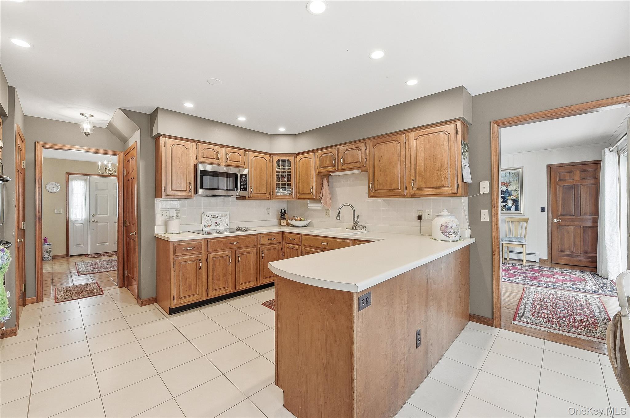 183 High Meadows Road Walden, NY 12586 - Photo 11 of 44 Kitchen with light countertops, stainless steel microwave, glass insert cabinets, light tile patterned floors, and a peninsula