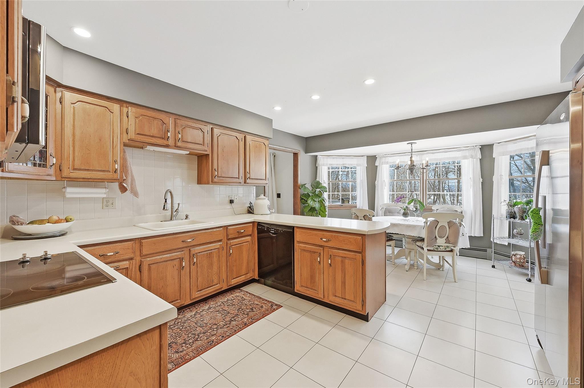 183 High Meadows Road Walden, NY 12586 - Photo 12 of 44 Kitchen with light countertops, black appliances, tasteful backsplash, light tile patterned floors, and brown cabinetry