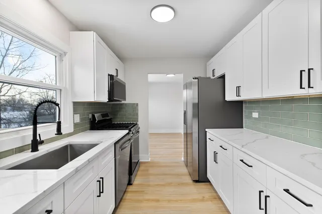 a kitchen with granite countertop a sink dishwasher a stove and a refrigerator with wooden floor