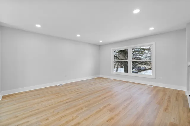 an empty room with wooden floor and window
