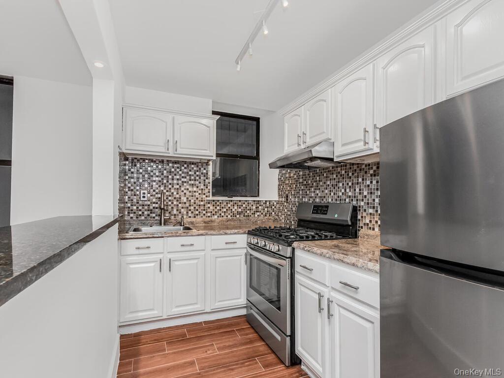 581 Academy Street, Unit GLE Manhattan, NY 10034 - Photo 6 of 18 a kitchen with white cabinets and stainless steel appliances