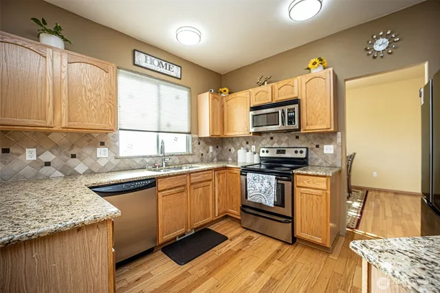 a kitchen with stainless steel appliances granite countertop a stove a sink and a microwave