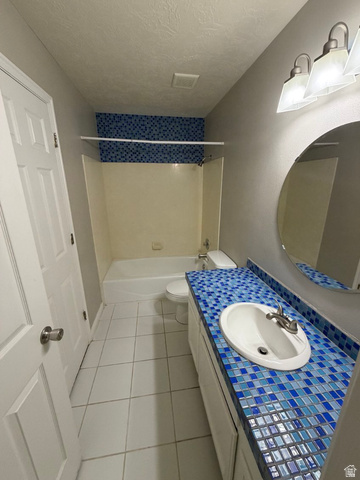 1563 South 600 East Springville, UT 84663 - Photo 18 of 30 Bathroom featuring a white vanity with a blue mosaic tile countertop, an oval-shaped mirror, a white drop-in sink with a brushed nickel faucet, a white toilet, and a white bathtub with blue mosaic tile surround