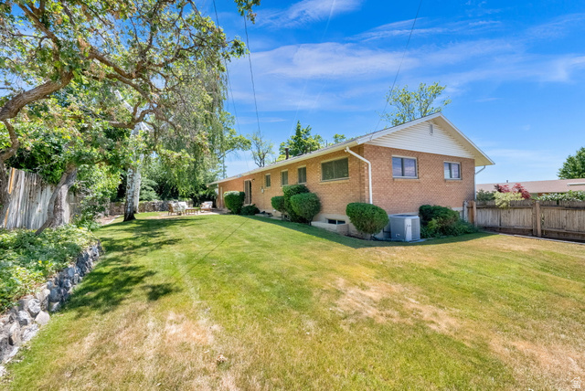 1783 South 500 East Bountiful, UT 84010 - Photo 23 of 30 Expansive backyard featuring a manicured lawn, mature trees, and a rock retaining wall