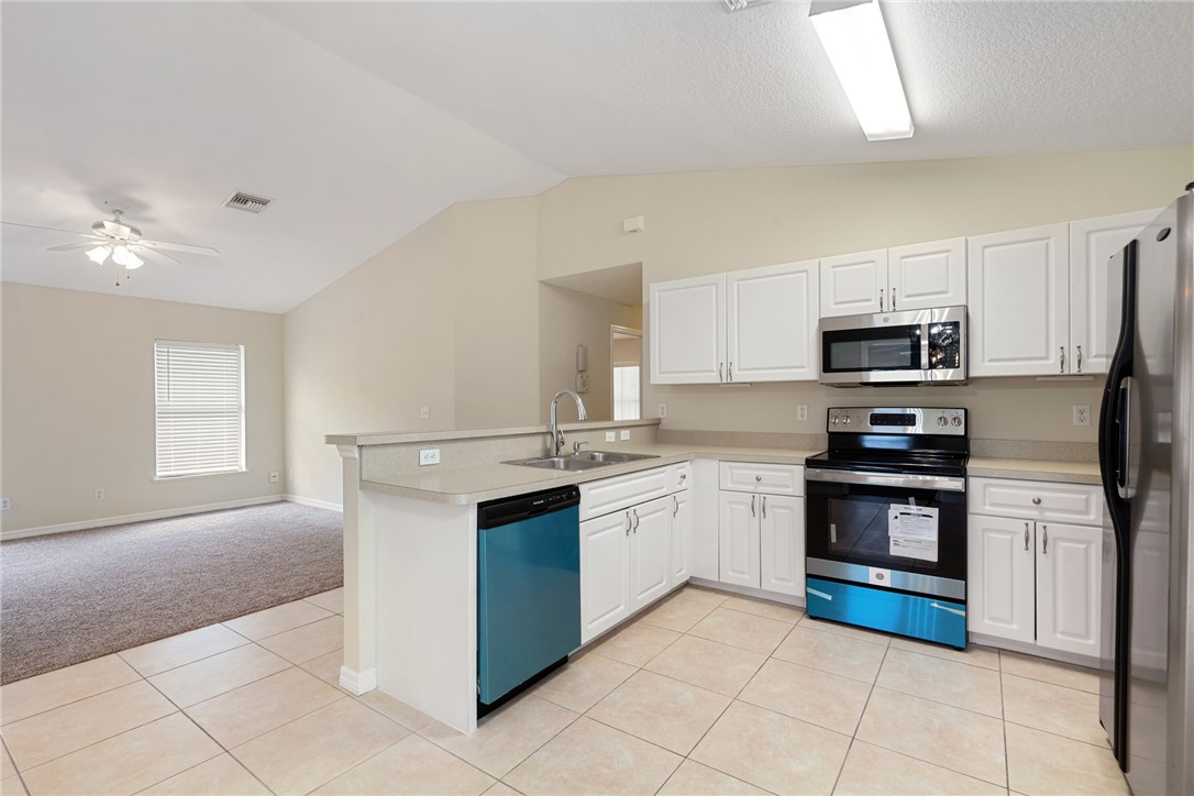a kitchen with stainless steel appliances granite countertop a stove top oven a sink dishwasher and a refrigerator