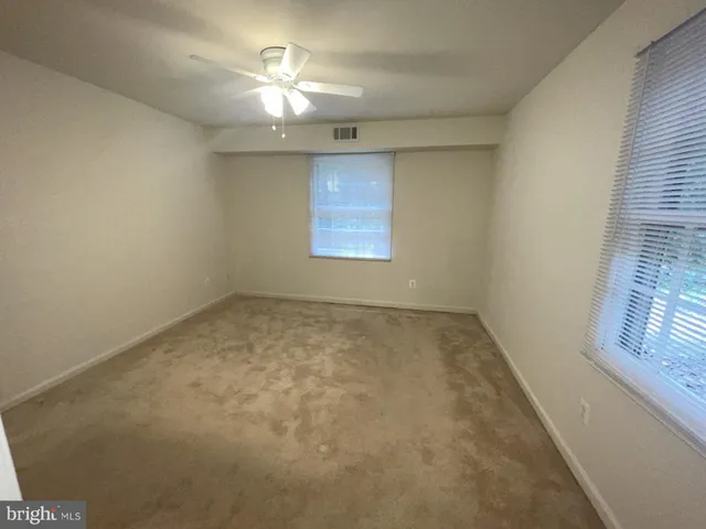 an empty room with windows and fan