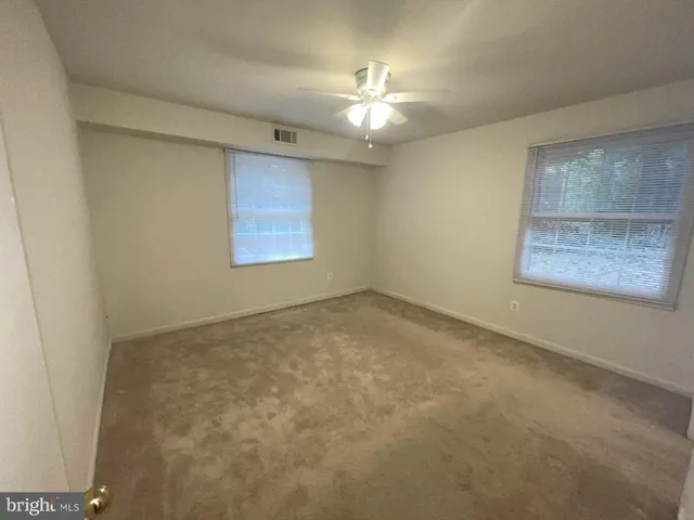 an empty room with a chandelier fan and windows