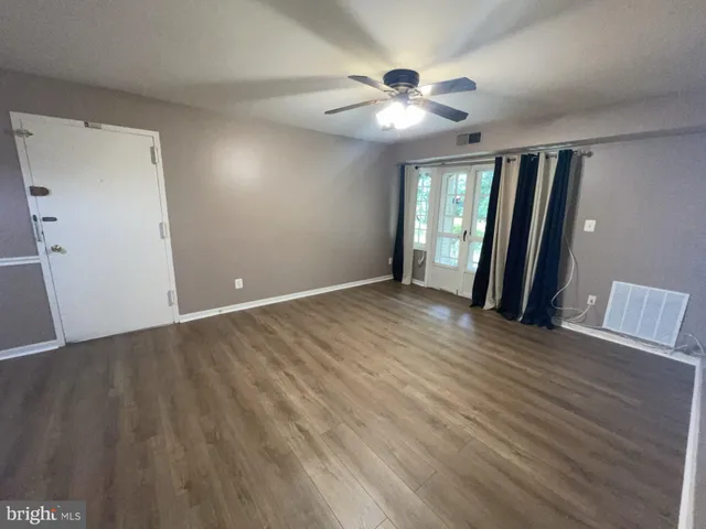 a view of an empty room with wooden floor and a window